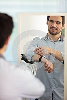 young businessman getting dressed front mirror