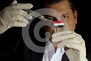 Young businessman gives a financial injection to Egyptian flag i