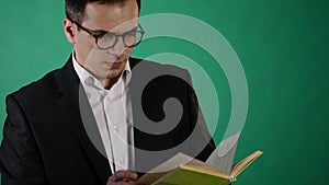 Young businessman with glasses reading a book on green backgraund