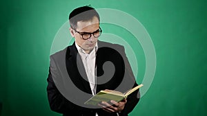 Young businessman with glasses reading a book on green backgraund