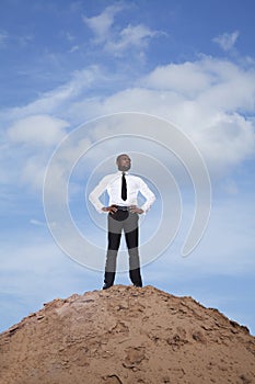 Young businessman with hands on hips in the desert