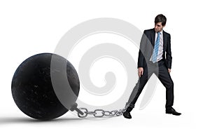 Young businessman has chained big metal ball to his leg. Isolated on white background.