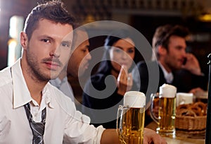 Young businessman having beer in pub