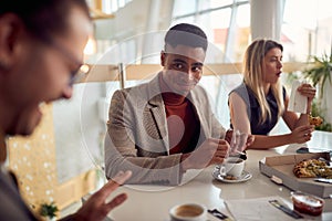 Young businessman is having a good time while sitting at the table in the company building during a lunch break and enjoys a