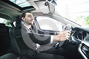 Young businessman in his car. Driver of luxuty car. Handsome man drive car.