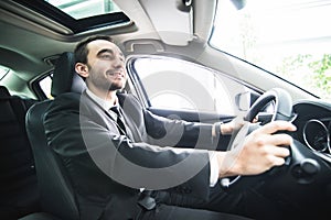 Young businessman in his car. Driver of luxuty car. Handsome man drive car.