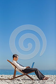 Young businessman on his deck chair using his laptop