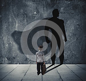 Young businessman with his shadow of super hero on the wall. Concept of powerful small man