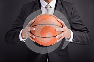 Young businessman holding basketball ball