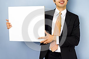 Young businessman holding blank sign