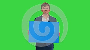 Young businessman holding blank sign looking at camera on a Green Screen, Chroma Key.