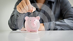 Young businessman holding coins in pig piggy bank, money saving concept yes future