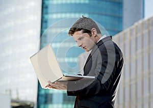 Young businessman holding computer laptop working urban business outdoors