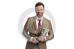 Young businessman holding his trophy proudly and smiling