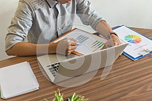 Young businessman holding pen and reading financial report