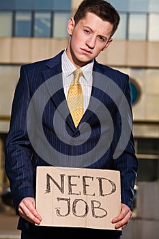 Young businessman holding sign Need Job outdoors