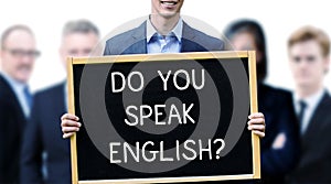 Young businessman holding a sign with the words Do You Speak Eng