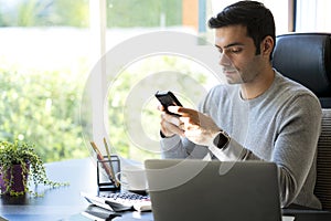 Young Businessman at home working on laptop. Man holding Mobile phone and using his mobile phone. Work from home