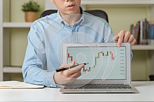 Young businessman or investor pointing on stock tickers or Cryptocurrency trading graphs to teach about investing new stock photo