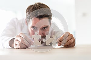 Young businessman joining two matching puzzle pieces