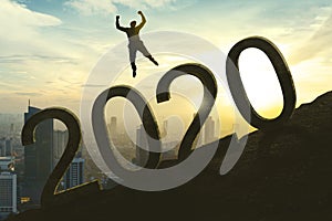 Young businessman jumping above number 2020
