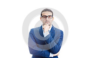 Young businessman keeps hand under chin, Thoughtful gesture, isolated over white background. Business worker wears glasses looking