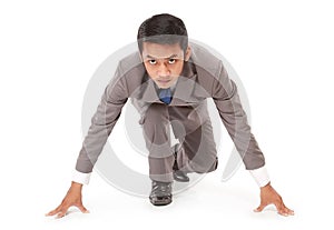 Young businessman kneeling as if about to start a race