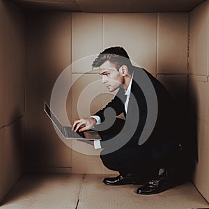 Young Businessman with Laptop in Cardboard Box.