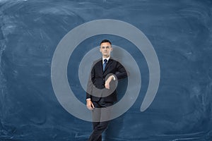 Young businessman is leaning to copy space on the blue chalkboard background