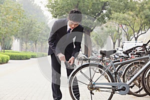 Young businessman locking up his bicycle on a city street in Beijing photo