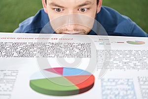 Young businessman looking at documents with business charts and diagrams