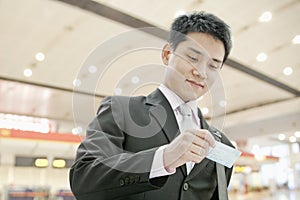 Young businessman looking down and checking his ticket at the airport