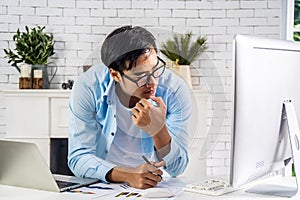 Young businessman looking at laptop pondering over problem solution, worried man gaze at computer screen thinking about decision