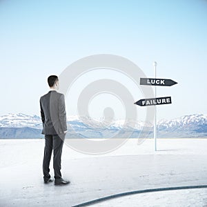 Young businessman looking on luck and failure sign post