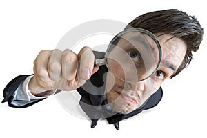 Young businessman is looking through magnifying glass. Isolated on white background. View from above