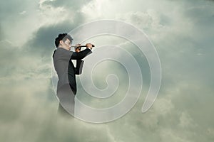 Young businessman looking through telescope in a dreamlike cloud