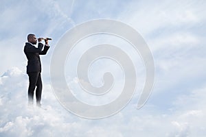 Young businessman looking through telescope in a dreamlike cloud world