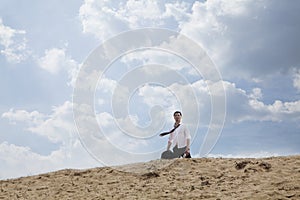 Young businessman lost and walking through the desert, distant