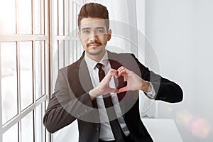 Young businessman in love shows heart sign