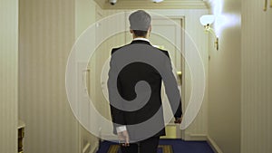 Young businessman with a luggage going in a hotel lobby and entering his room