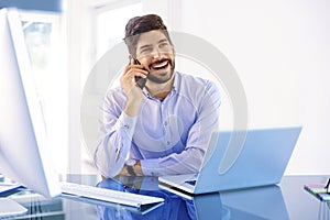 Young businessman making a call while working on laptop