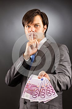 Young businessman making silence gesture and holding euro bankn