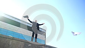 Young businessman manager stands on street against background of office lease on edge, scatters papers in air, throws