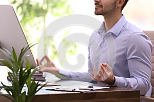Young businessman meditating at workplace. Zen concept