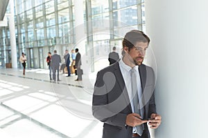 Young businessman with mobile phone looking away in lobby office