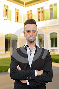 Young businessman outdoors with arms crossed vertical shot