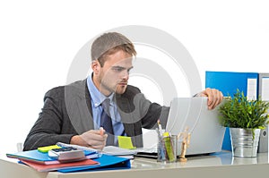 Young businessman overworked looking worried sitting at office computer desk in stress