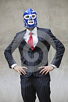 Young businessman in pinstripes suit and wrestling mask over gray background photo