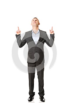 Young businessman pointing upwards