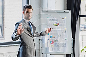 young businessman pointing at whiteboard with business charts